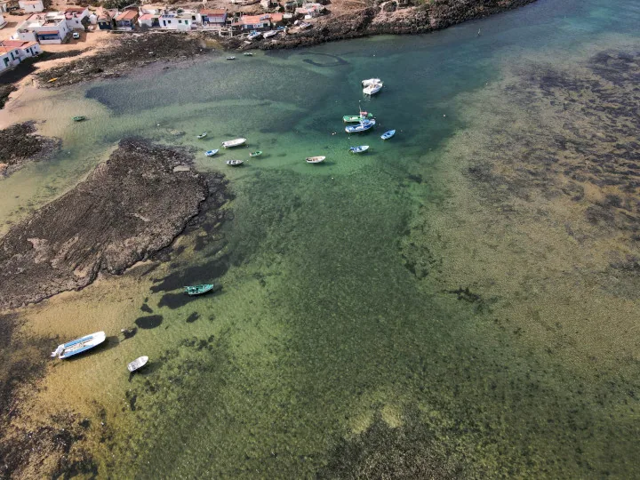 Grunt turkist vann og små båter ved kysten i Corralejo